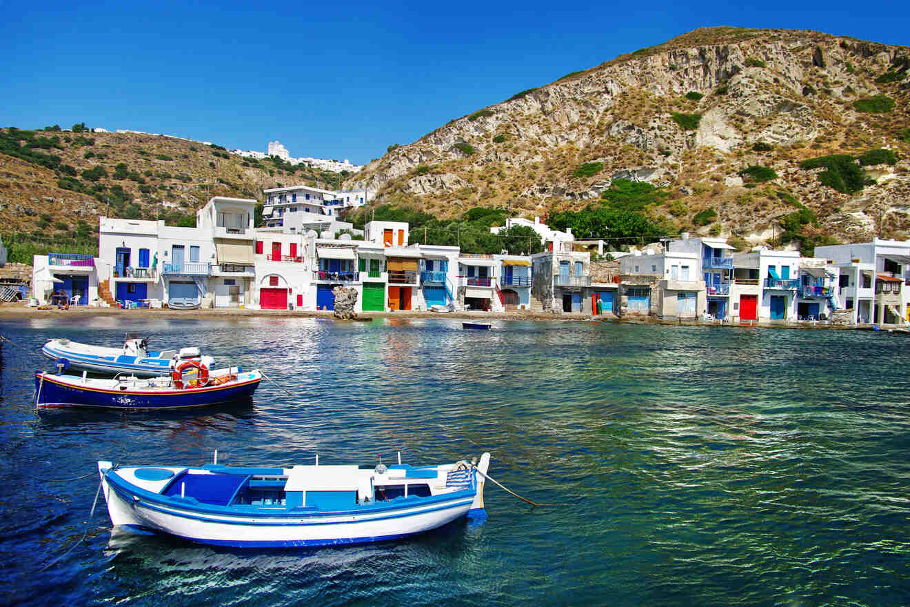 Colorful fishing boats anchored in a picturesque Greek bay with vibrant buildings along the shoreline