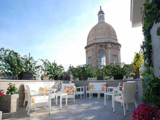 A patio with white furniture and a dome in the background.