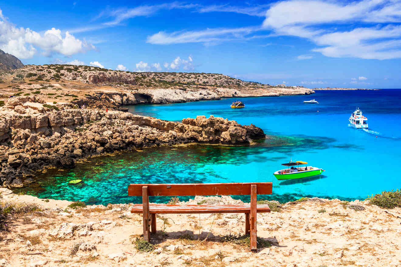 Serene seaside viewpoint with a bench overlooking clear blue waters, boats, and rugged coastline in Ayia Napa, Cyprus