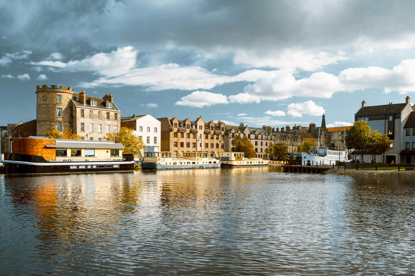 The serene waters of Leith reflect the historical buildings of The Shore, Edinburgh, under a dramatic sky, creating a picturesque waterfront scene