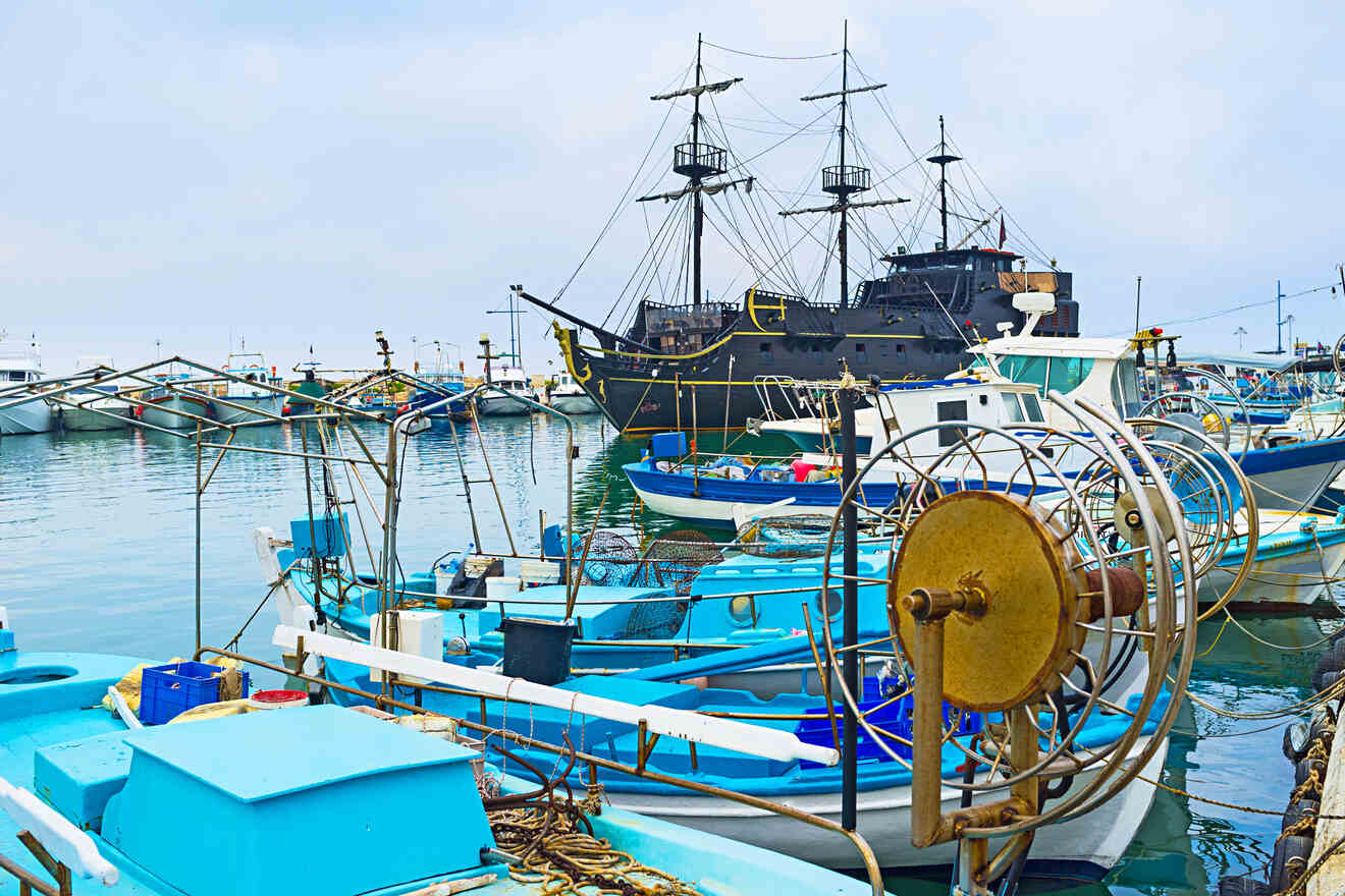 Colorful fishing boats and a replica pirate ship moored at a marina in Cyprus