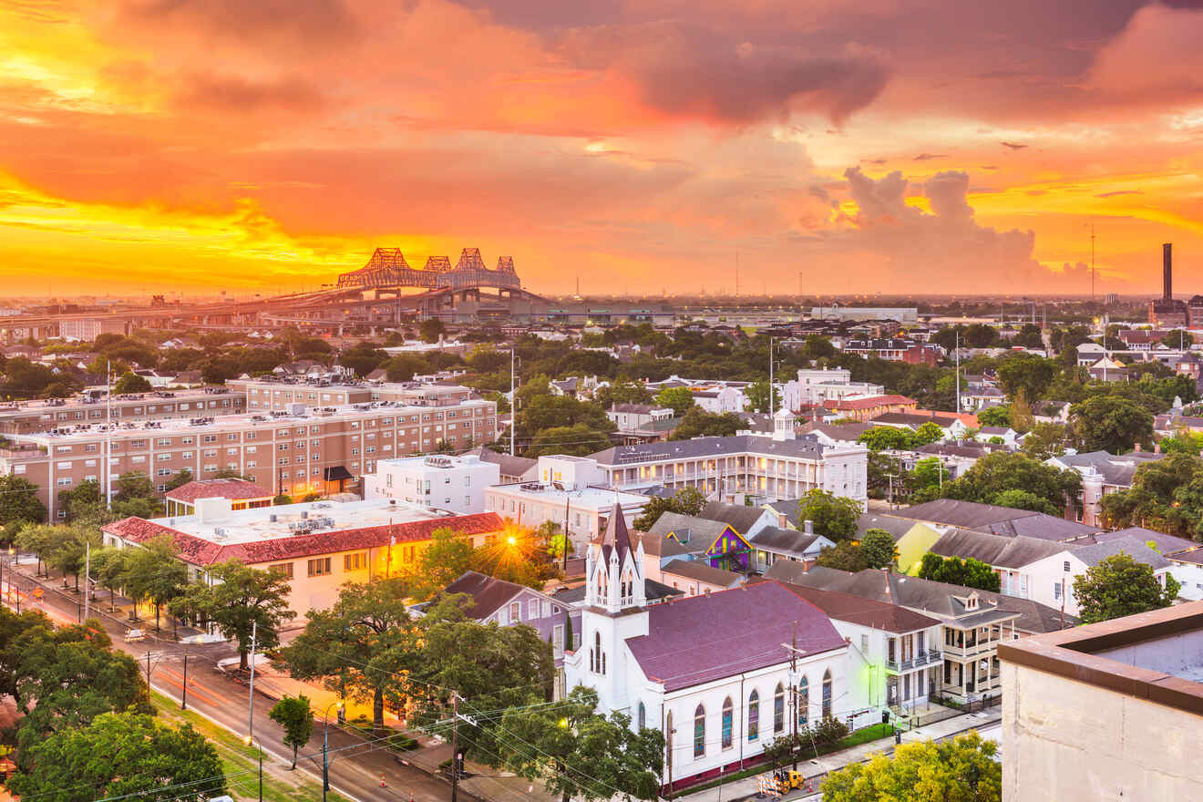 A cityscape of New Orleans, featuring a sunset sky, a bridge in the background, and distinctive architecture, including a prominent white church in the foreground.