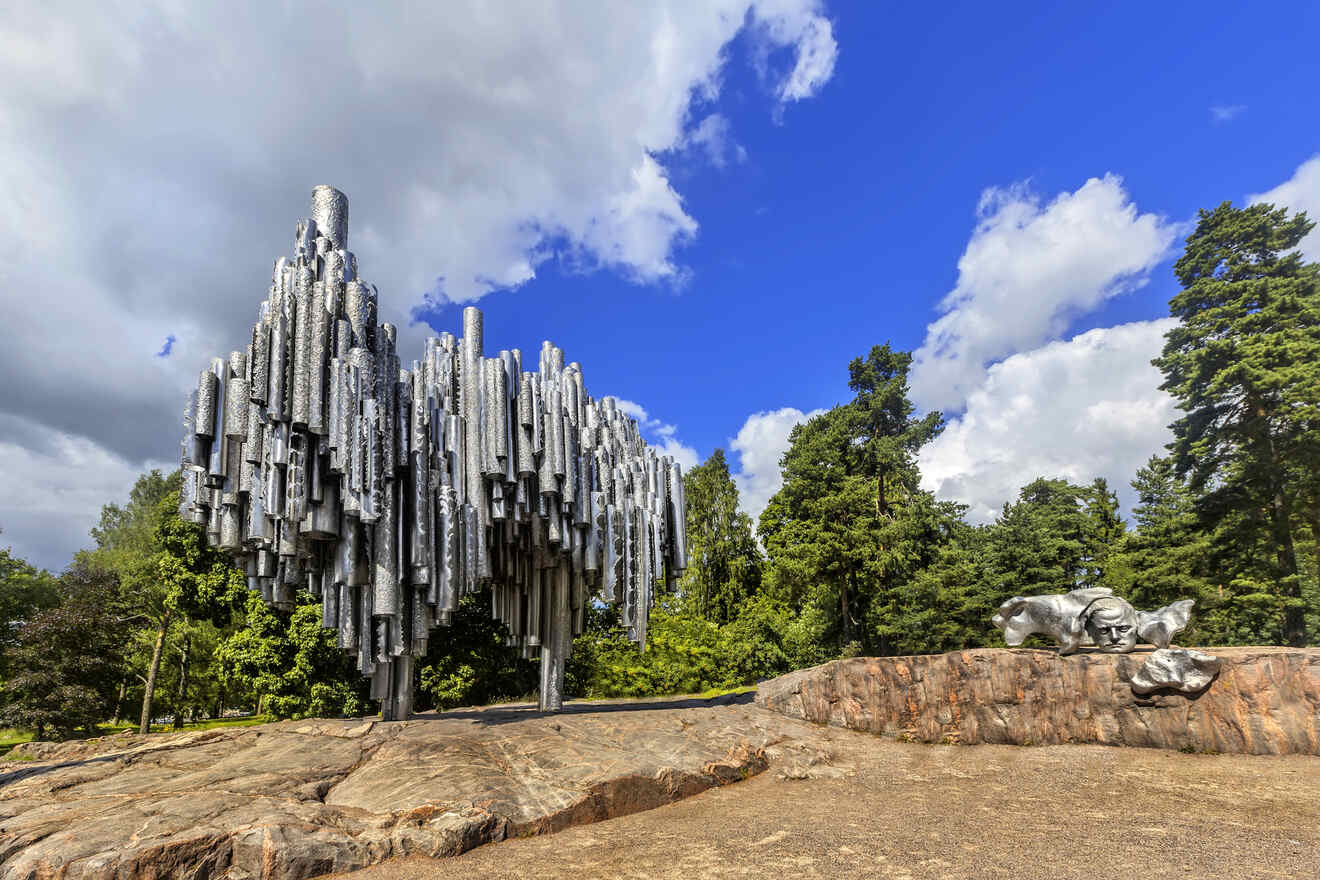 The Sibelius Monument in Helsinki, a striking steel sculpture resembling organ pipes, set against a backdrop of blue sky and green trees