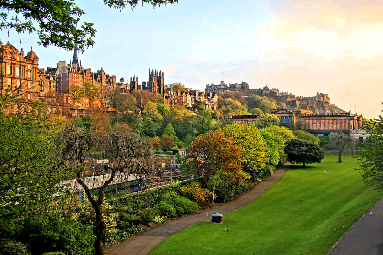 A vibrant sunset casts golden hues over the greenery of Princes Street Gardens with the Edinburgh skyline, including the castle, providing a majestic backdrop