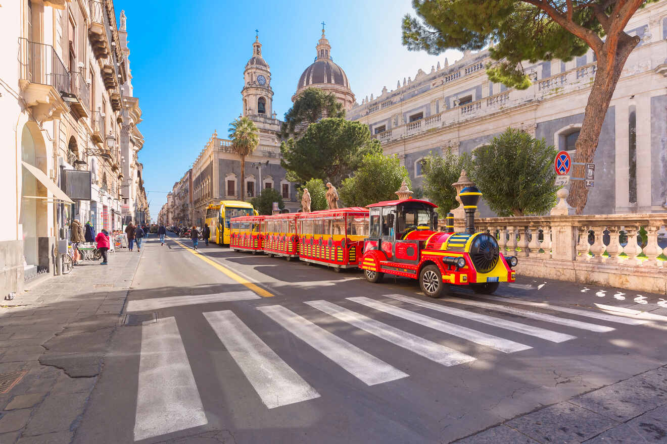 A red and yellow train traveling down a city street.