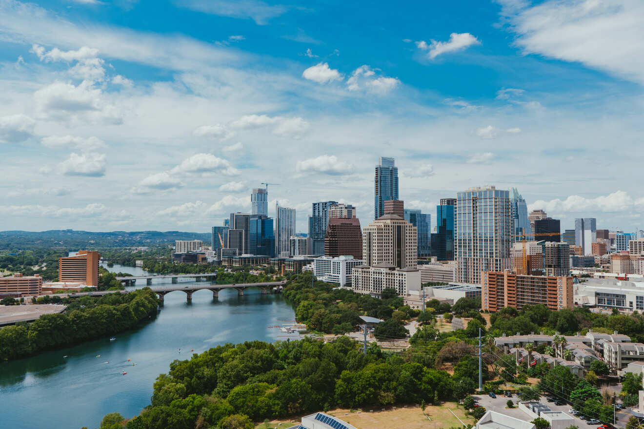 The skyline of Austin, Texas with a river with bridges surrounded by trees on the left side and tall skyscrapers and buildings on the right side of the picture