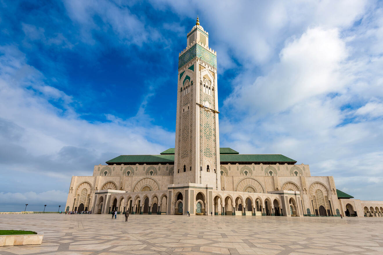 The majestic Hassan II Mosque against a blue sky in Casablanca, Morocco, showcasing its intricate architecture and tall minaret.