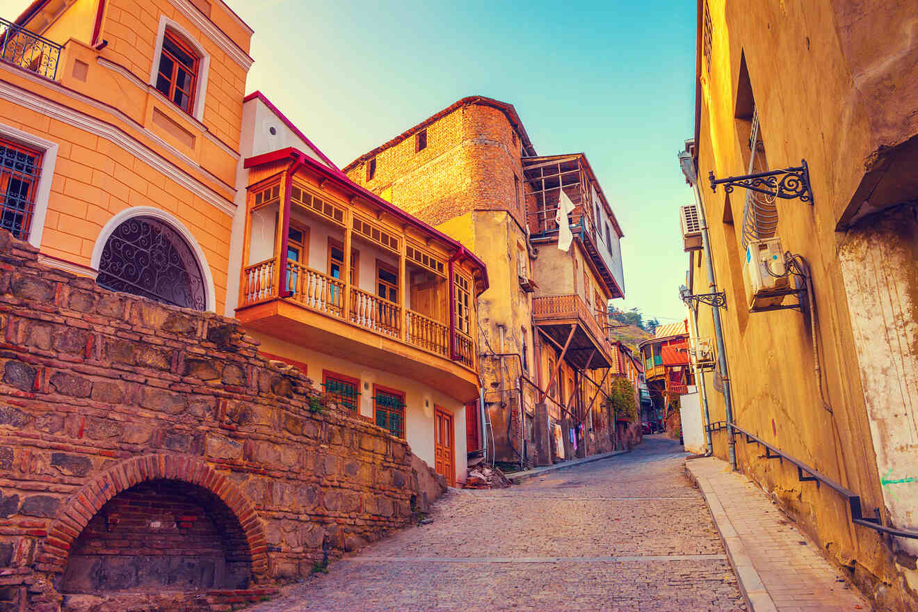 A quaint street in Tbilisi during golden hour, highlighting traditional Georgian architecture with wooden balconies and a cobbled street, radiating warmth and local culture