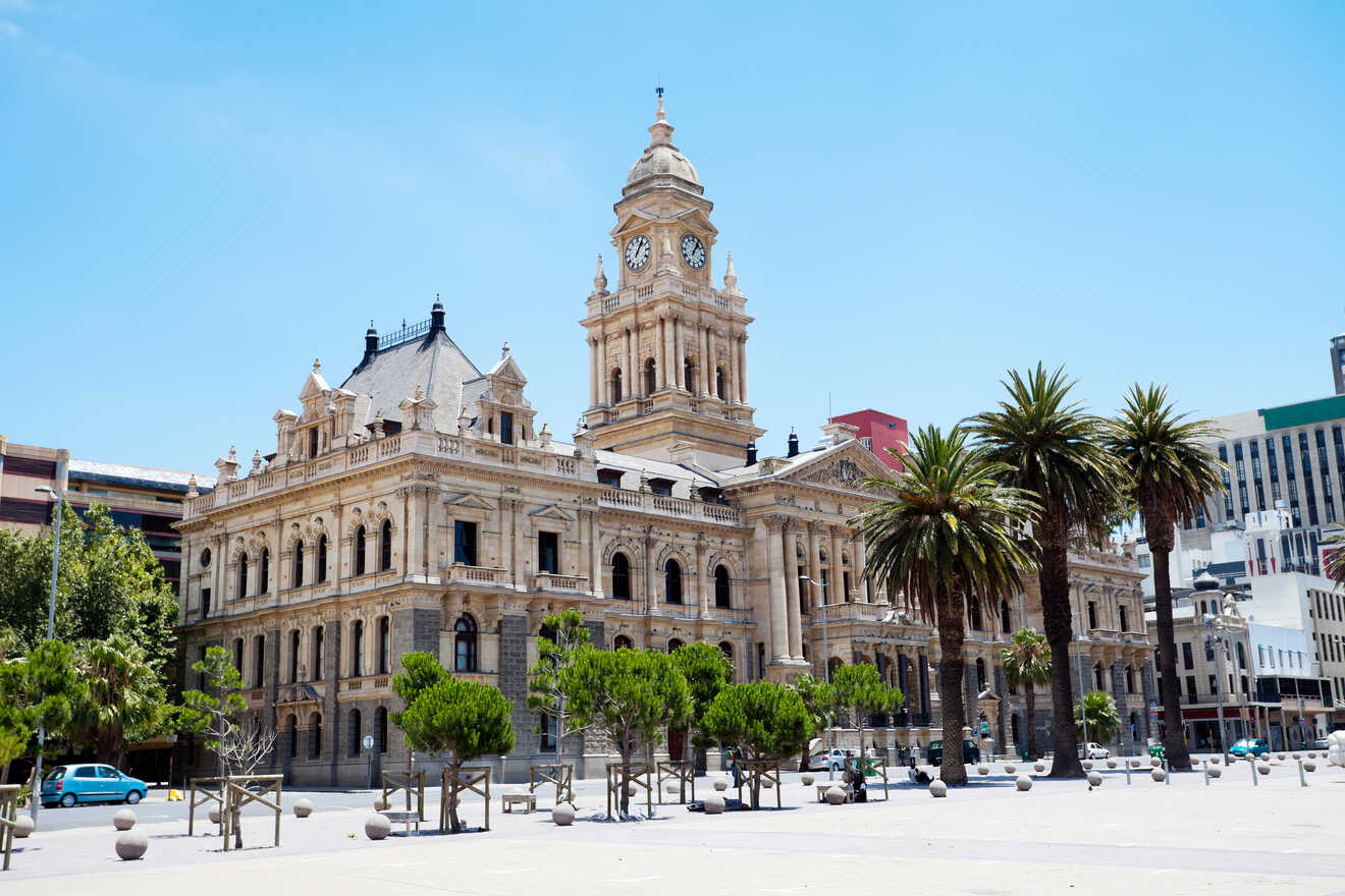 Majestic historical building with clock tower, flanked by palm trees under a clear blue sky.