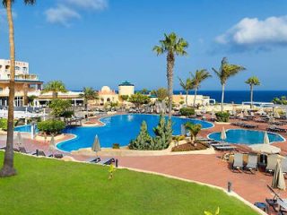 Resort pool area with palm trees and ocean view.