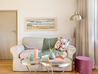Cozy corner with a plush sofa, pink and green accents, and a circular glass coffee table.