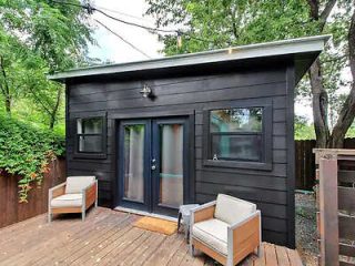 A small wooden cabin with a deck and chairs.