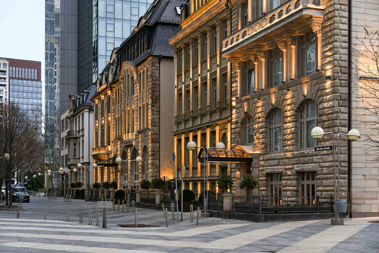 Twilight view of a traditional and modern architectural fusion in Frankfurt am Main, with street lamps illuminating the stone façade of a historic building