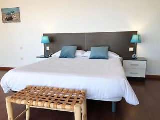 Sleek bedroom with large bed, blue accents, and wooden bench