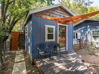 the exterior of a blue wooden cabin with small deck with chairs on it