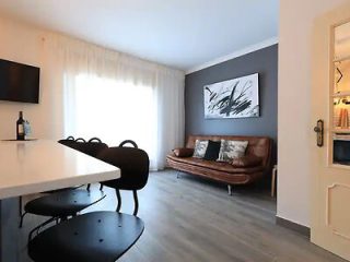 Contemporary dining and living area with a black table, leather couch, and abstract wall art