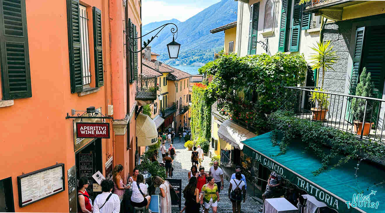 Busy, narrow cobblestone street in Bellagio, Lake Como, lined with bright buildings, shops, and a crowd of tourists enjoying the local scene
