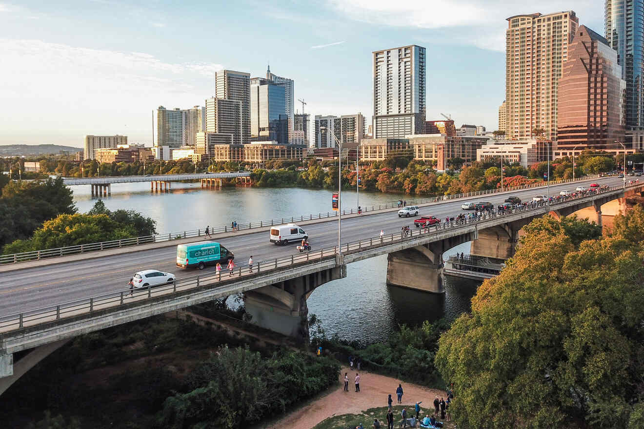 A bridge over a river in and tall buildings in the background on the river bank in South Congress in Austin, Texas.