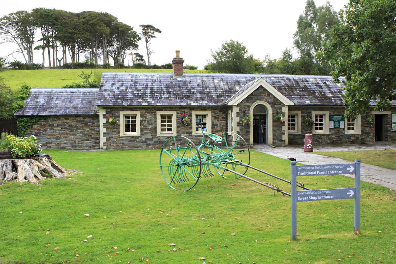 Traditional Irish stone building with a slate roof serving as an entrance to a farm, set against a backdrop of tall trees