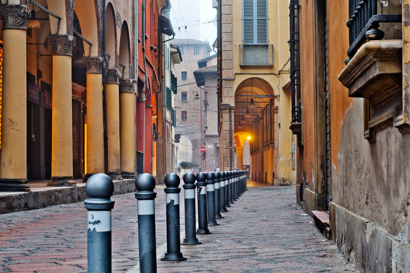 Charming alley in Bologna with traditional porticoes, cobblestone pavement, and glowing street lights, evoking a sense of old-world Europe.
