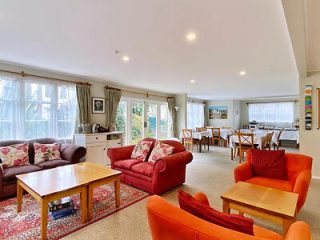A large, open-plan living and dining area with plush red and orange sofas, a carpeted floor, and ample seating