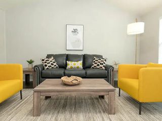 A living room with yellow chairs, grey sofa and a coffee table.