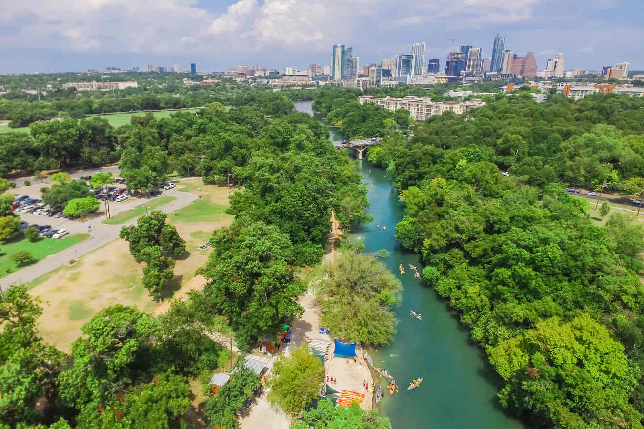 Aerial view of a river surrounded by trees and a skyline of the Zilker neighborhood in the city of Austin, Texas.