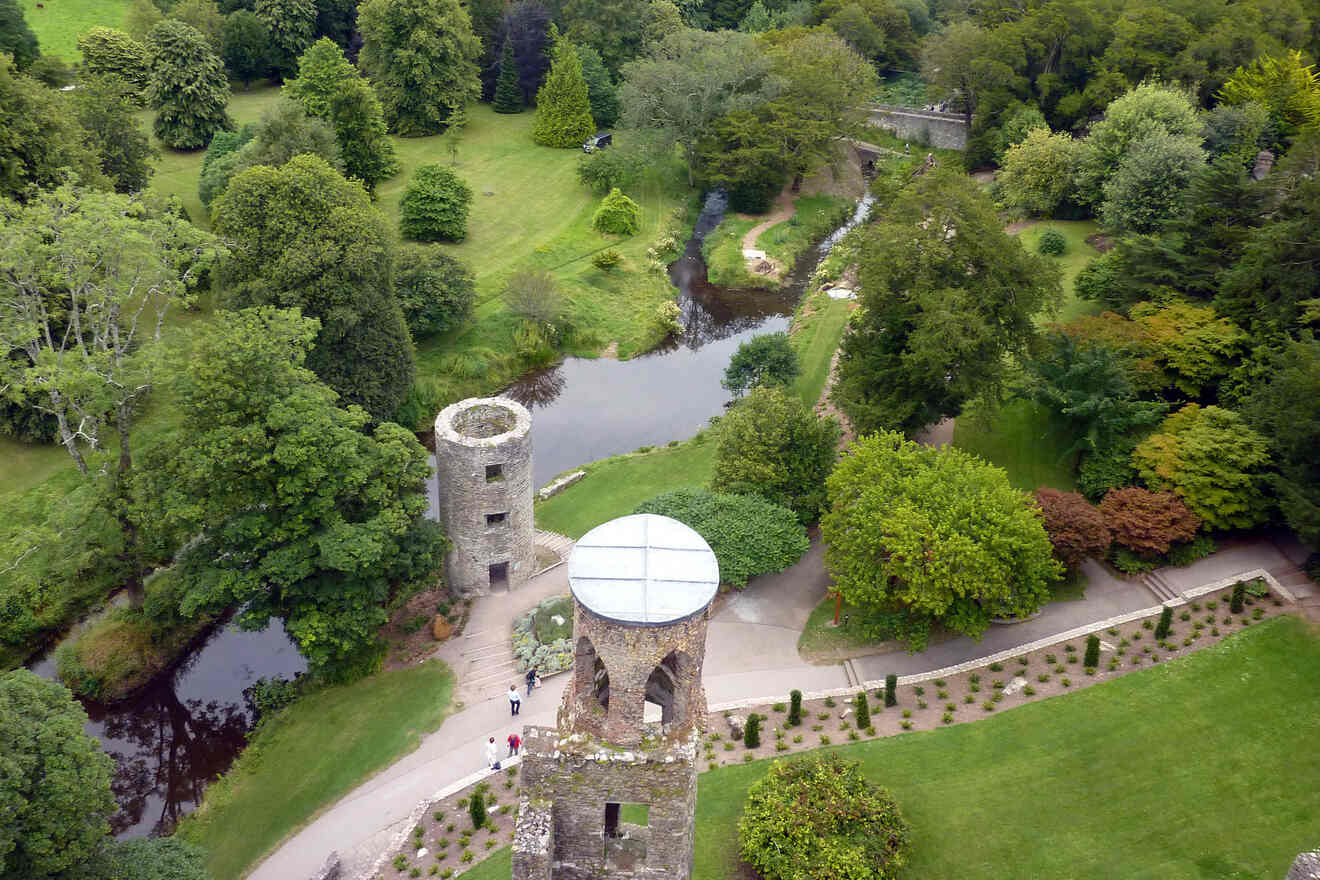 An aerial view of a historic tower and roundhouse surrounded by greenery and a meandering stream in a serene park