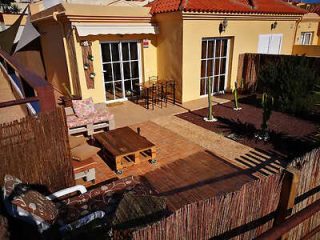 Private outdoor patio with wooden table and wicker chairs.