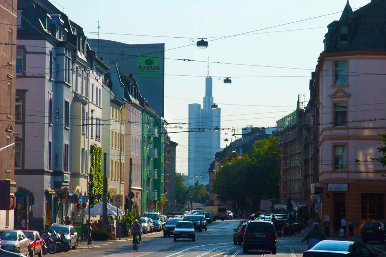 A street view in Frankfurt with diverse architectural styles, leading towards the contemporary skyscrapers under a hazy sky