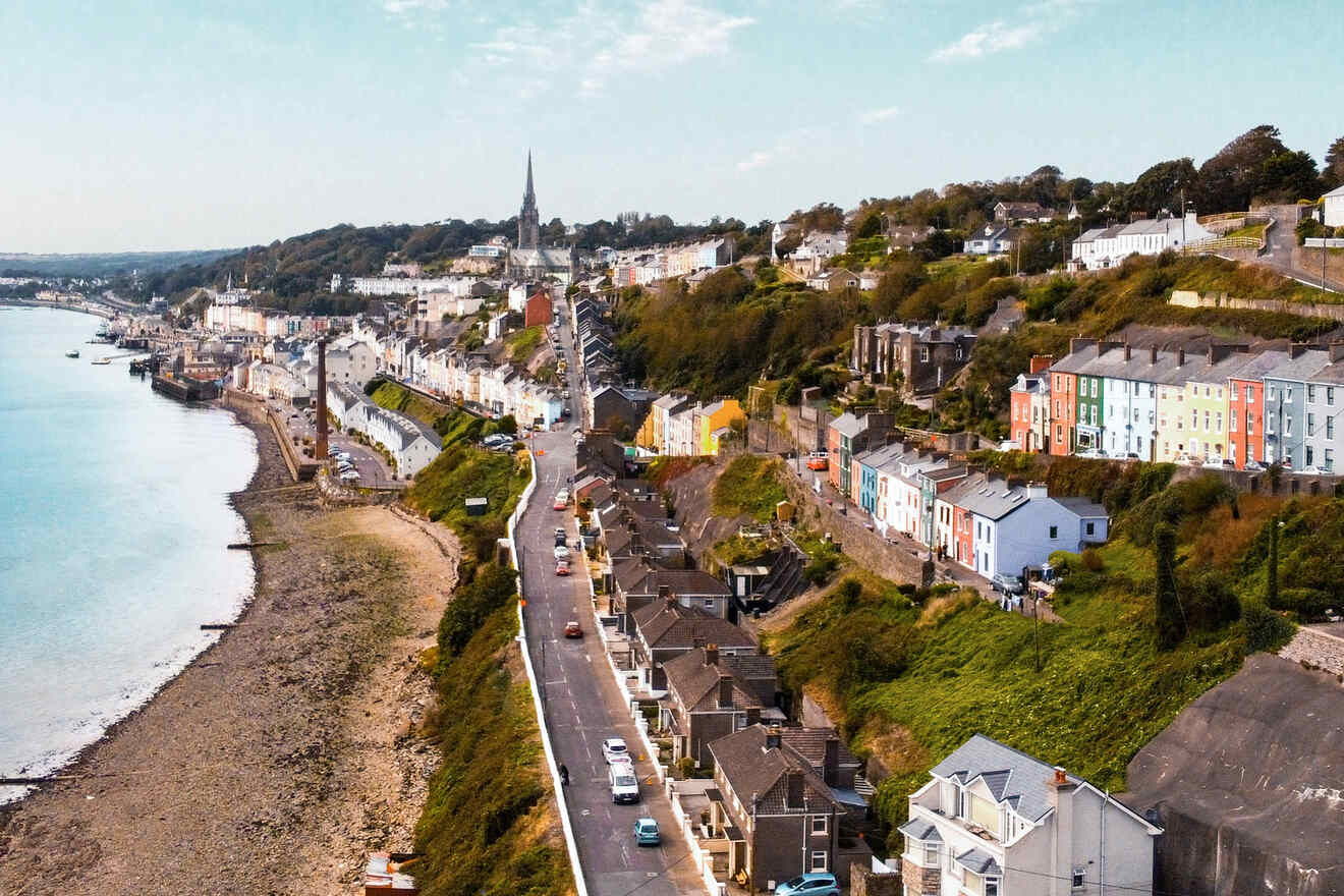 The scenic coastal town of Cork, Ireland with colorful houses lining the hillsides along a curved roadway adjacent to the sea