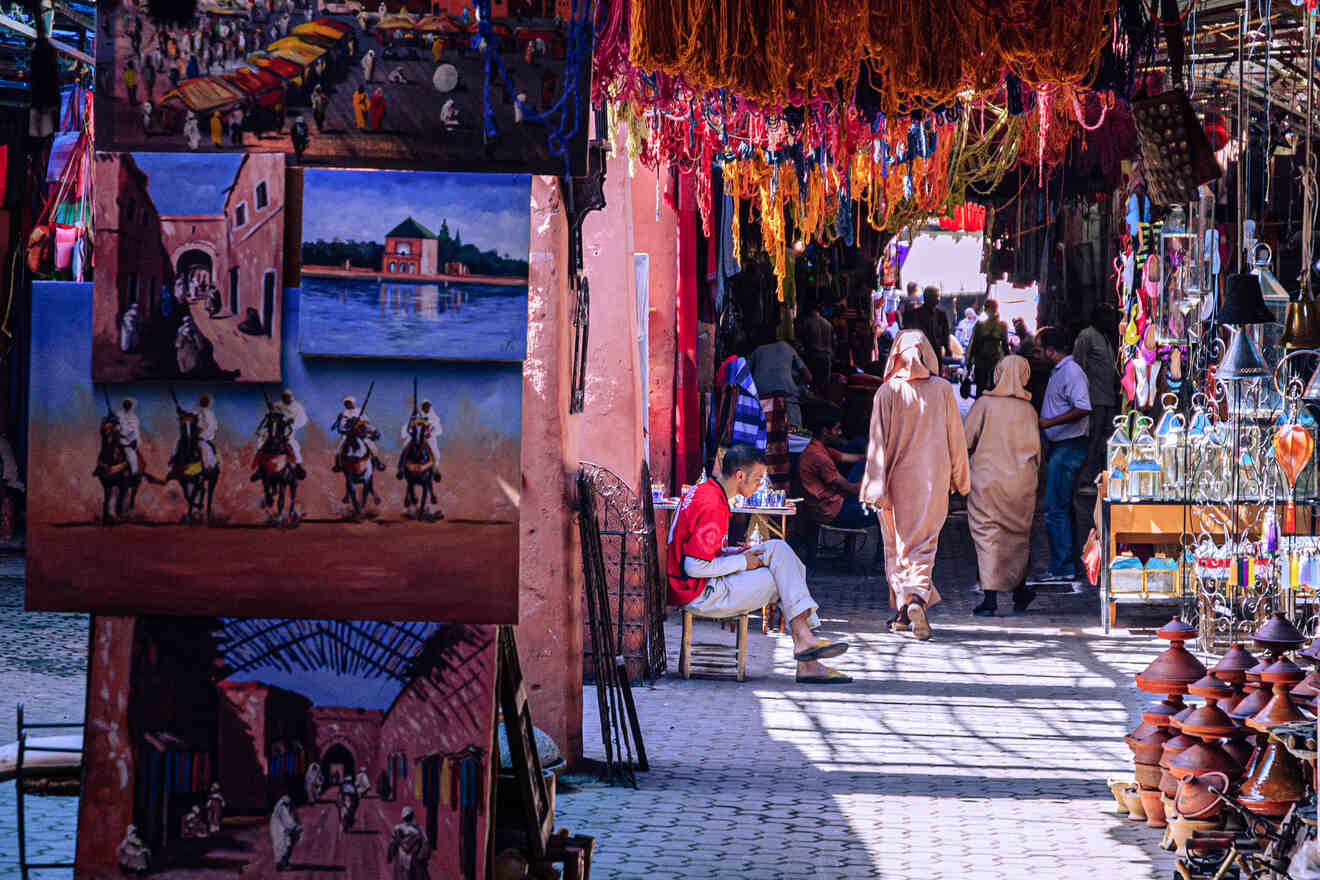 Vibrant Moroccan market scene with colorful art, textiles, and ceramics on display as locals and tourists wander through the alley.