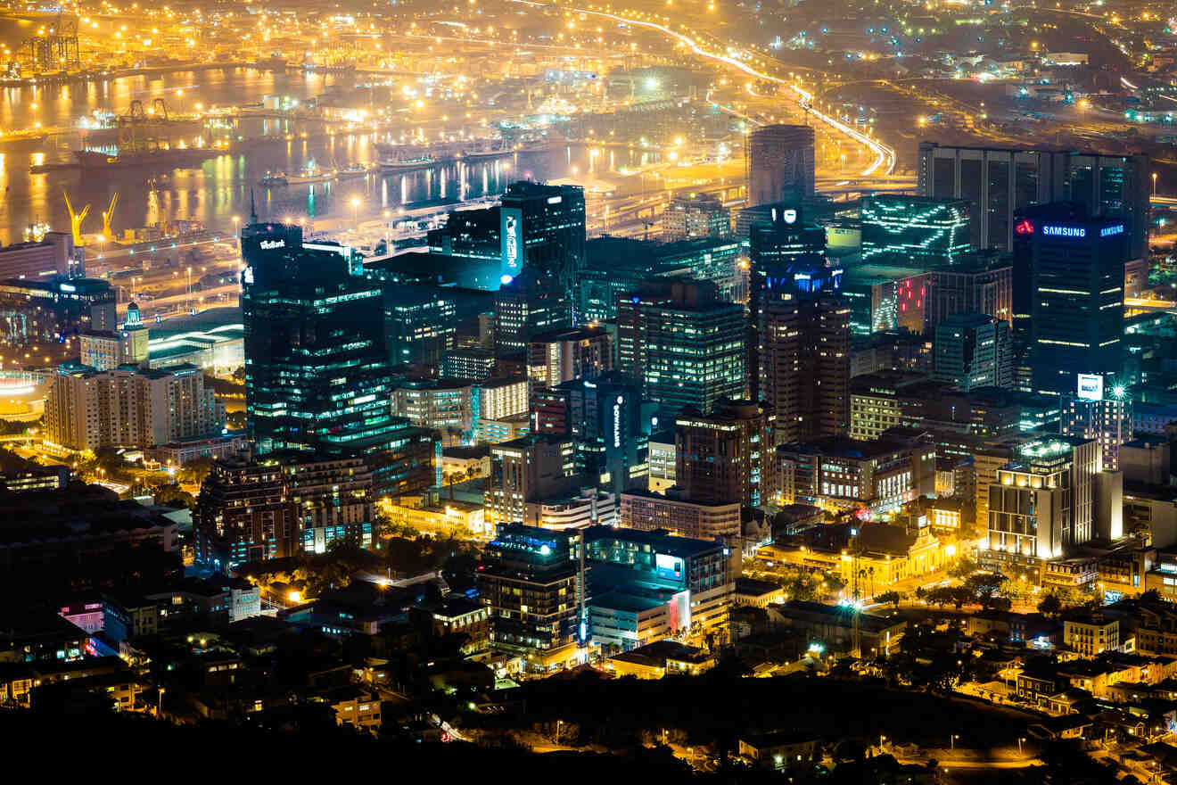 Nighttime Cape Town cityscape with illuminated skyscrapers, vibrant streets, and a busy port, reflecting the city's energetic pulse.