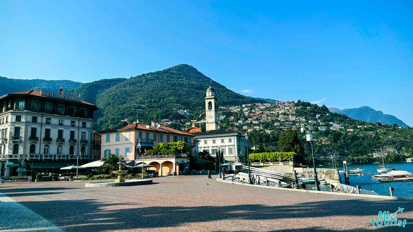 The spacious Piazza Cavour in Como with the neoclassical facade of the cathedral, lakeside views, and surrounding mountains under a blue sky