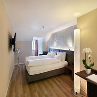 Modern and minimalist hotel room with a large bed, sleek furnishings, and ambient lighting