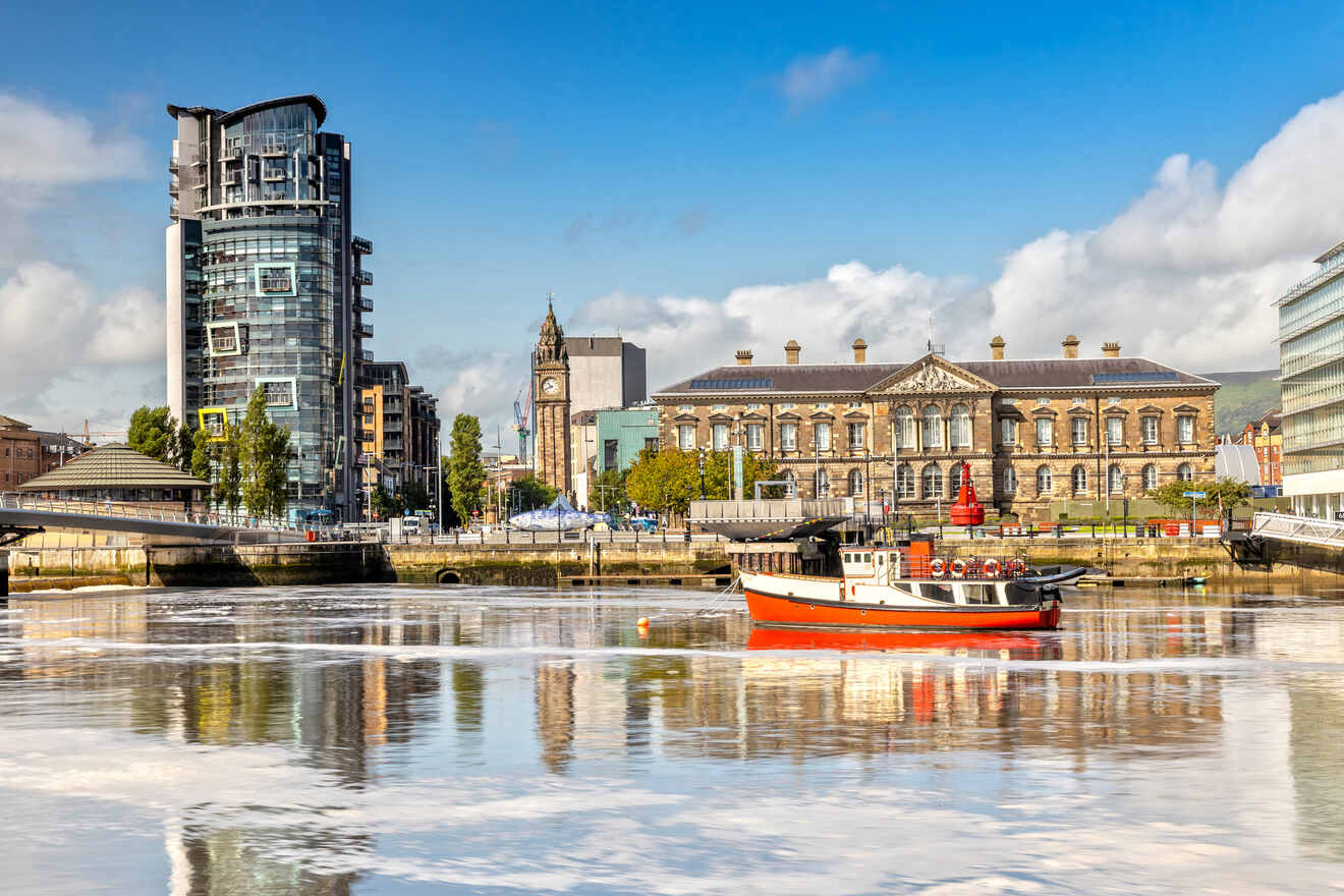 Urban riverscape featuring the Custom House in Belfast, with a red boat in the foreground and modern buildings juxtaposed against the classical architecture