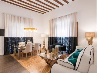 Stylish living space with a white sofa, wooden ceiling beams, and a unique rustic coffee table, complemented by chic patterned tile accents