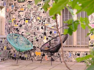 Artistic outdoor seating area with eclectic mosaic tile backdrop and stylish black wicker chairs