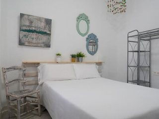 Minimalist white bedroom with whimsical mirrors, a simple shelf headboard, and artistic wall decor