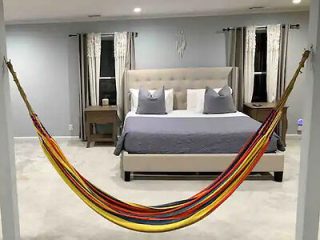 A modern bedroom with a unique hammock stretched across, adding a playful touch to the sophisticated decor featuring a king-sized bed