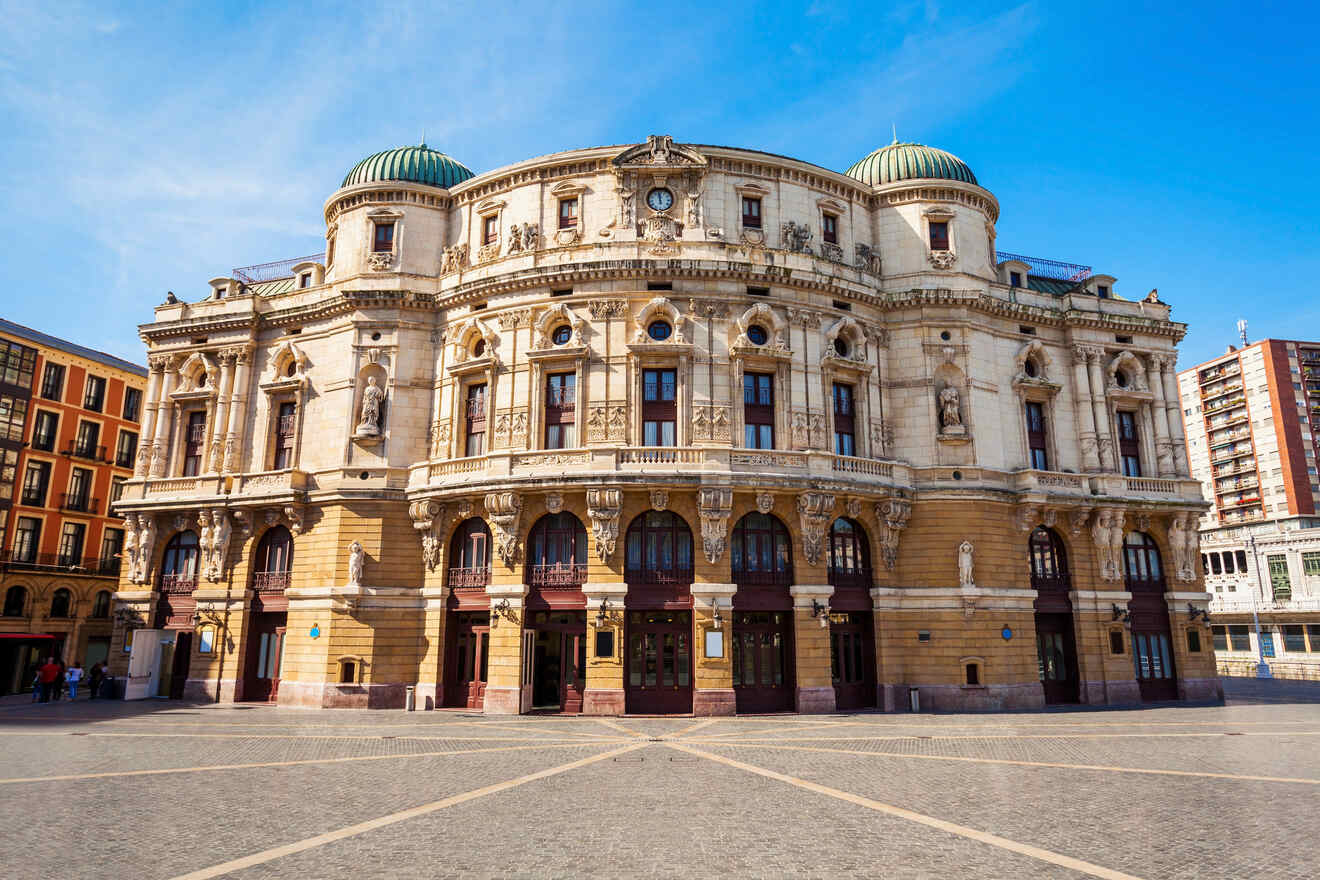 Exterior view of a grand European opera house with intricate Baroque architecture and sculptural details, set against a clear blue sky