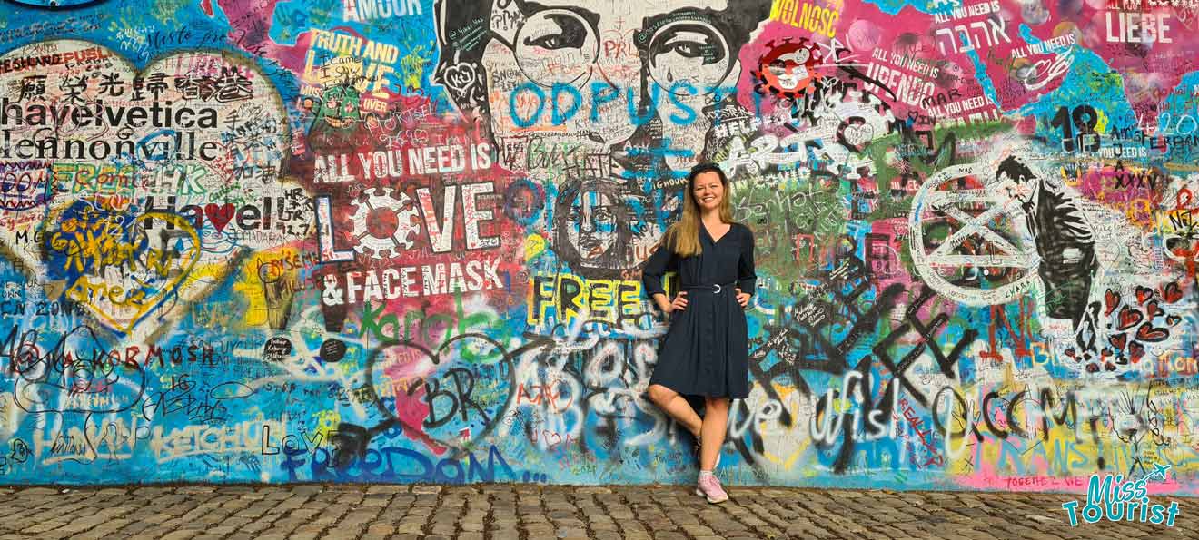 A woman standing in front of a graffiti covered wall.