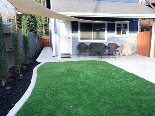 well-maintained backyard patio with a covered seating area and synthetic lawn