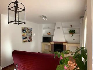 Cozy living space with a red sofa, white fireplace, and eclectic wall art under a classic lantern-style light fixture