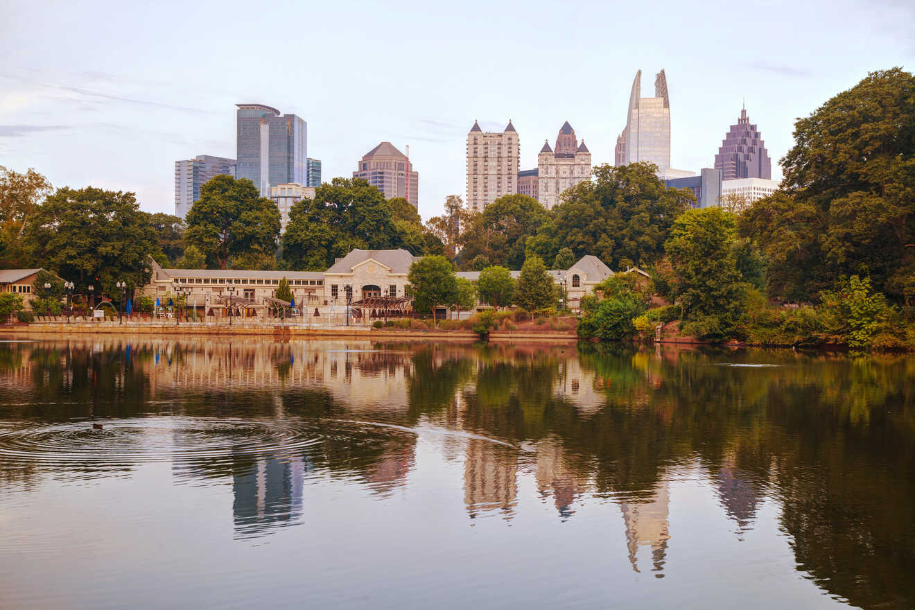 Serene city park scene in Atlanta with a calm lake reflecting the surrounding trees and the distant city skyline in the early evening
