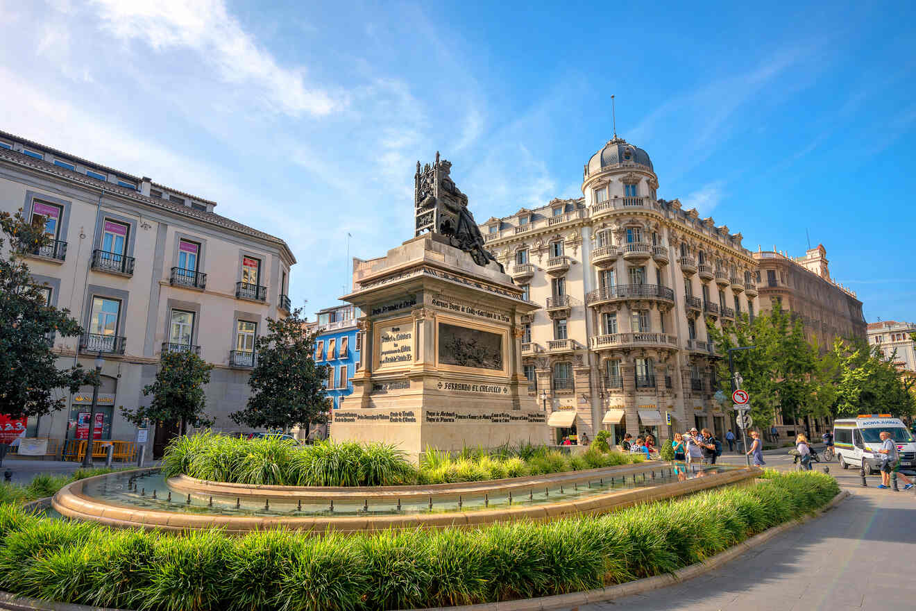 A monument honoring General Torrijos stands in a bustling square surrounded by classic European architecture under a clear blue sky in Granada, Spain