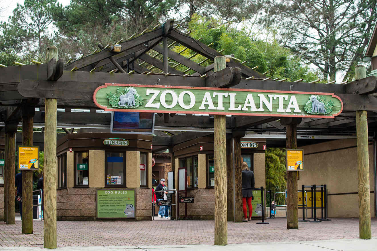 Entrance to Zoo Atlanta with a welcoming sign, ticket booths, and guests arriving, surrounded by lush greenery and clear signage.