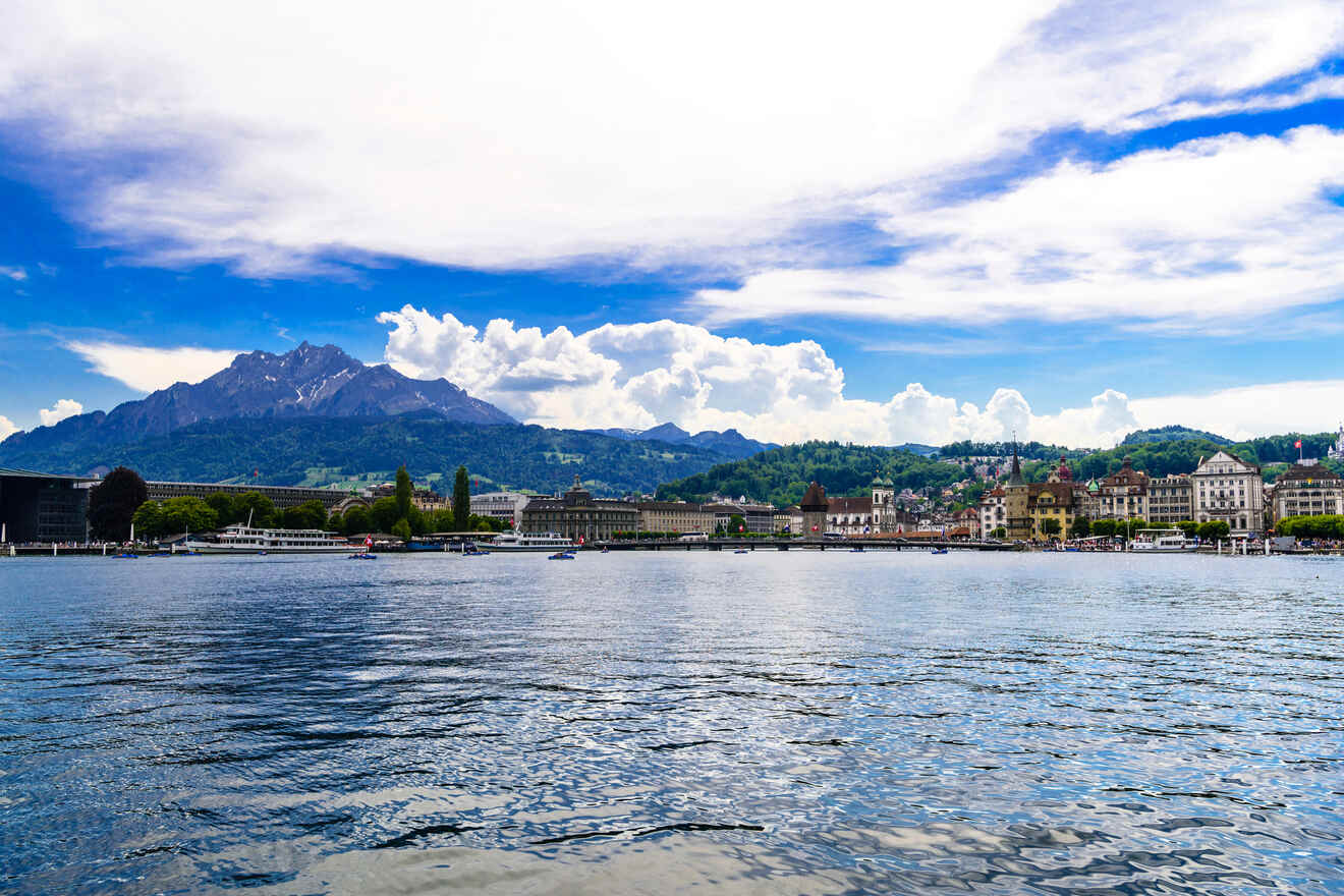 Expansive view of a lake with the cityscape and mountains in the background under a blue sky with wispy clouds