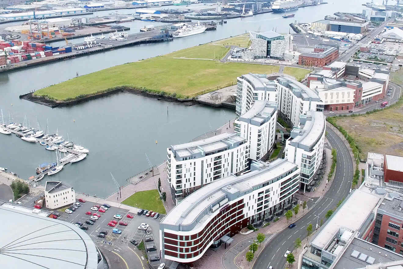 Aerial view of Belfast's waterfront development with contemporary architecture, the calm water of the river reflecting the urban landscape.