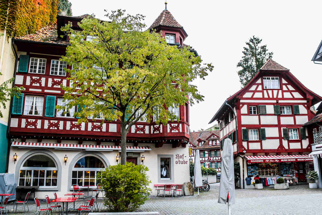 Picturesque Swiss street scene with colorful half-timbered buildings, outdoor cafe seating, and quaint shops